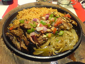 A mixed platter of beef and chicken fajitas wi...